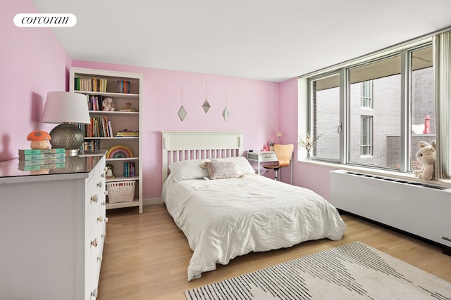 bedroom with radiator heating unit and light wood-style floors