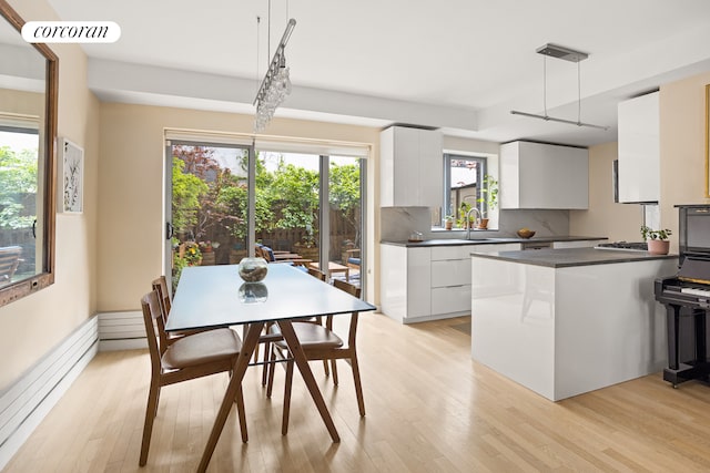 kitchen featuring modern cabinets, dark countertops, a baseboard radiator, white cabinetry, and light wood-style floors