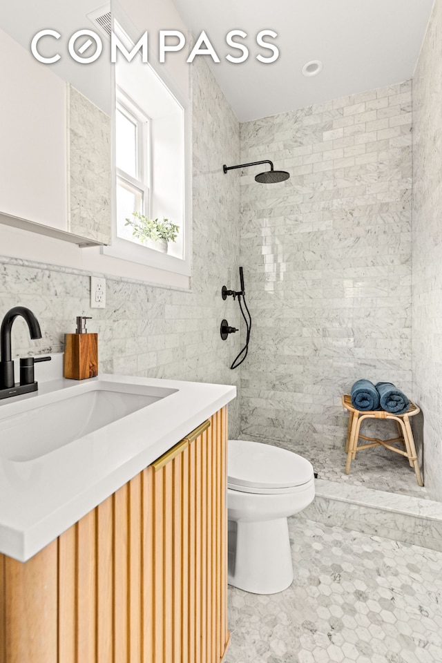 full bath featuring a tile shower, toilet, tile walls, and vanity