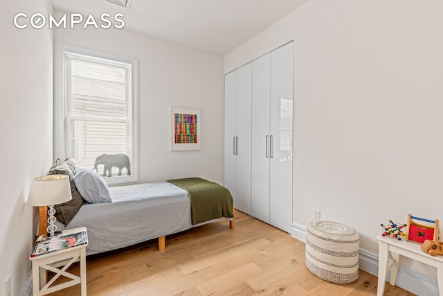 bedroom featuring light wood-style flooring, a closet, and baseboards