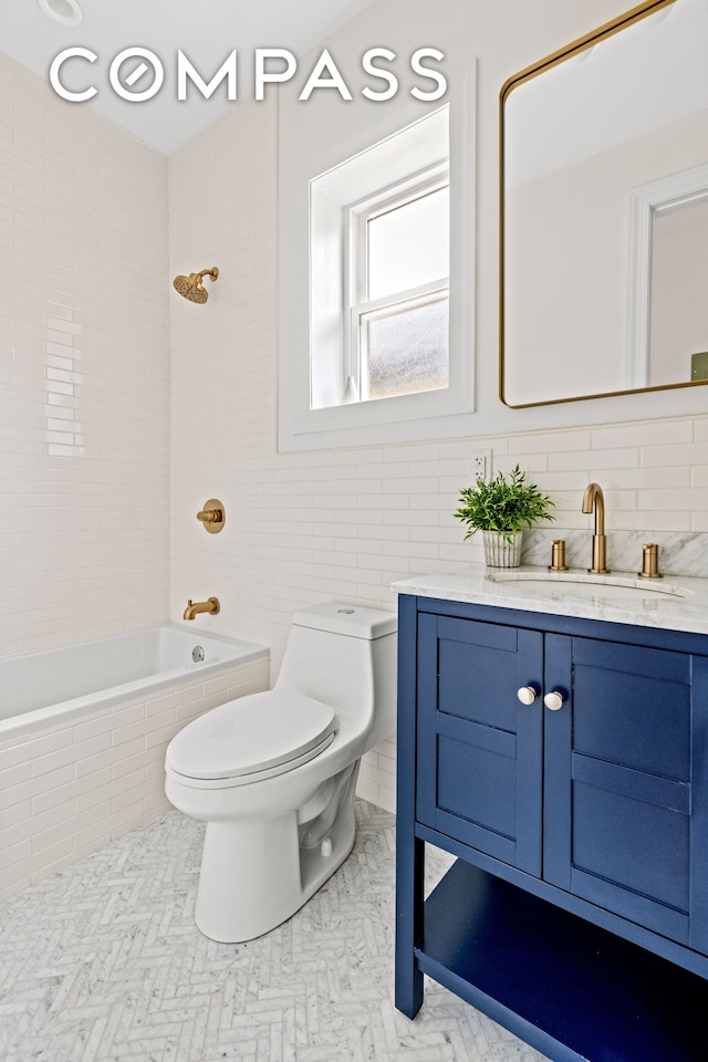 full bath with toilet, tile walls, vanity, and tiled shower / bath