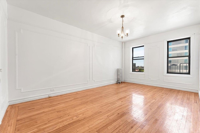 3400 Wayne Ave Unit C51, New York City, NY 10467 - spare room with radiator, a chandelier, light wood finished floors, and a decorative wall