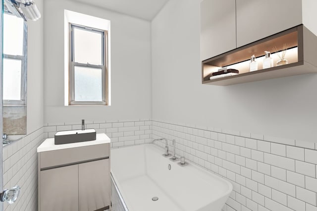full bath with tile walls, a bath, wainscoting, and vanity