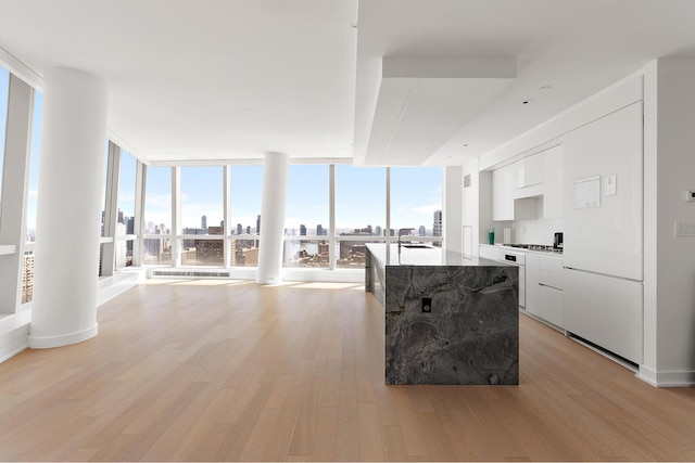 kitchen featuring modern cabinets, white cabinetry, light wood-style floors, floor to ceiling windows, and a skyline view
