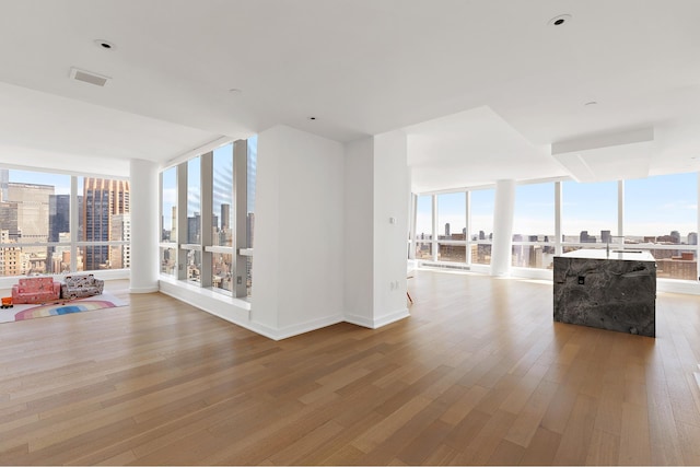 hall featuring wood finished floors, healthy amount of natural light, expansive windows, a city view, and baseboards