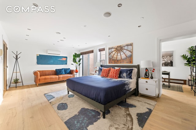 bedroom featuring a wall mounted air conditioner, light wood-type flooring, baseboards, and recessed lighting