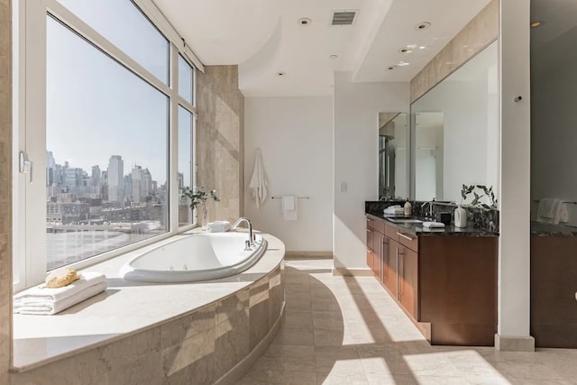 bathroom featuring a tub with jets, vanity, a skyline view, tile patterned floors, and baseboards