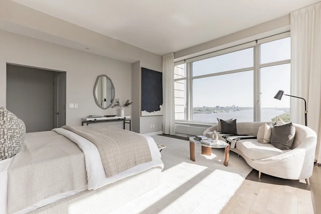 bedroom featuring a water view, baseboards, and wood finished floors
