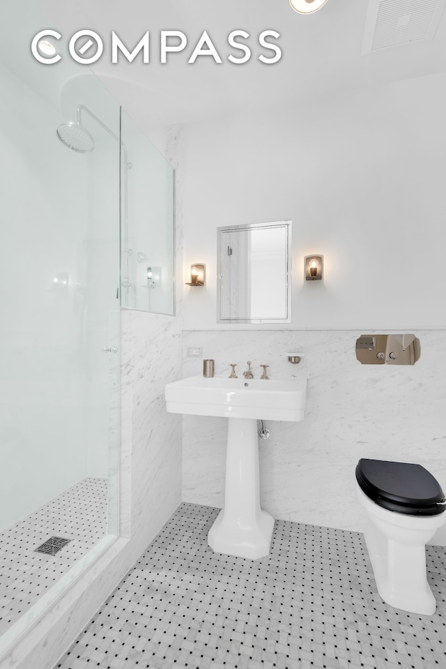 full bath with a walk in shower, tile walls, tile patterned floors, wainscoting, and toilet