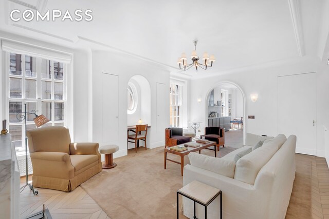 living room featuring arched walkways, a chandelier, and baseboards