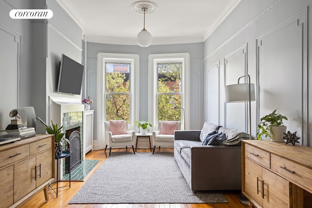 living area featuring ornamental molding, a tile fireplace, and wood finished floors