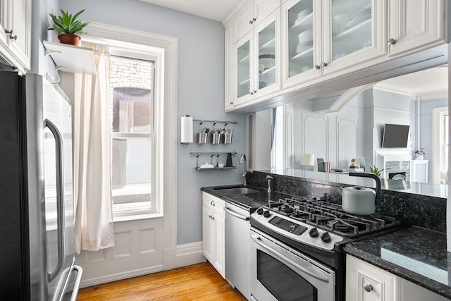 kitchen featuring appliances with stainless steel finishes, dark stone counters, white cabinetry, and glass insert cabinets