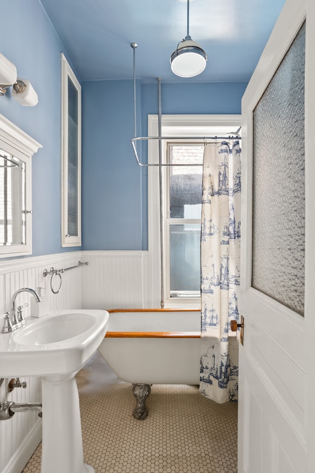 full bath with wainscoting, a freestanding tub, and a shower with shower curtain