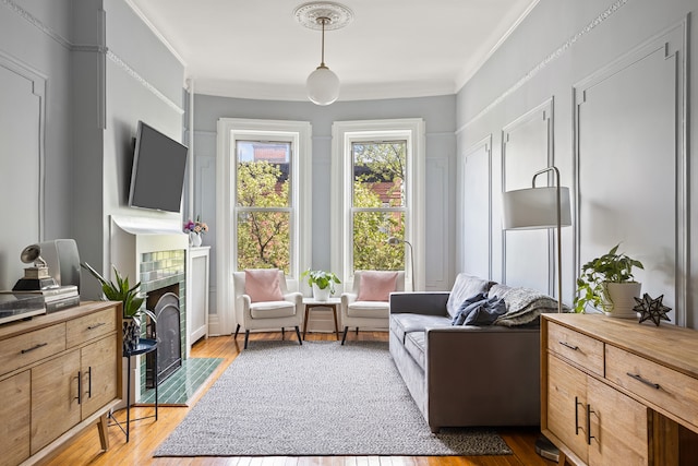 living area with crown molding, a tile fireplace, and wood finished floors