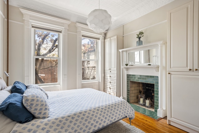 bedroom featuring light wood-style flooring and a tile fireplace