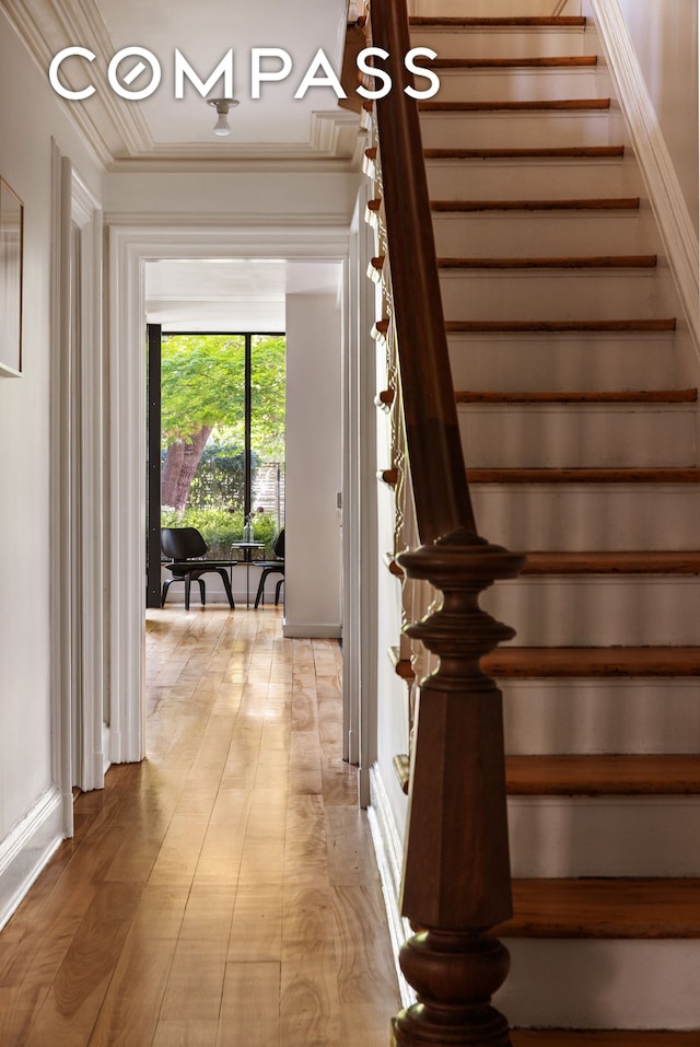 staircase featuring ornamental molding, baseboards, and wood finished floors