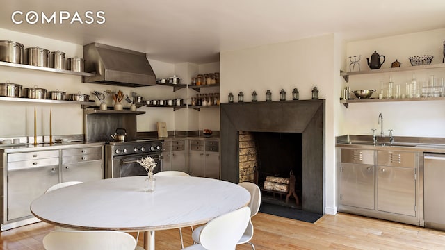 dining space featuring light wood finished floors, bar with sink, and a fireplace with flush hearth