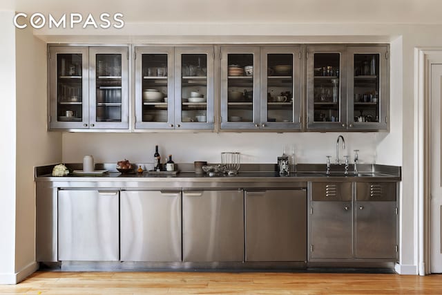 bar with light wood-style flooring, baseboards, and a sink
