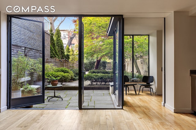 entryway featuring a wall of windows, hardwood / wood-style flooring, and baseboards