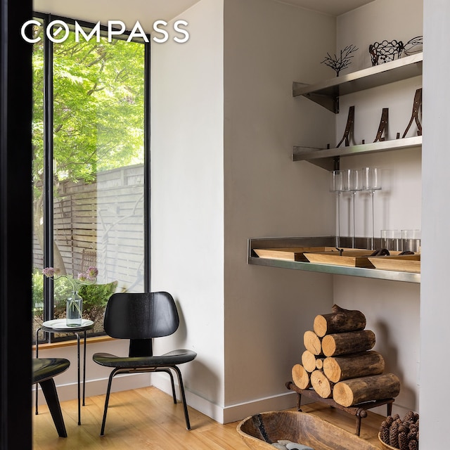sitting room featuring healthy amount of natural light, wood finished floors, baseboards, and bar area