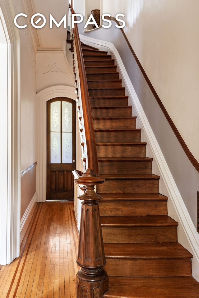 staircase with hardwood / wood-style floors, ornamental molding, and baseboards