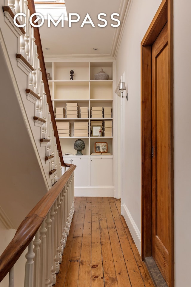 hall with crown molding, light wood-type flooring, and stairway