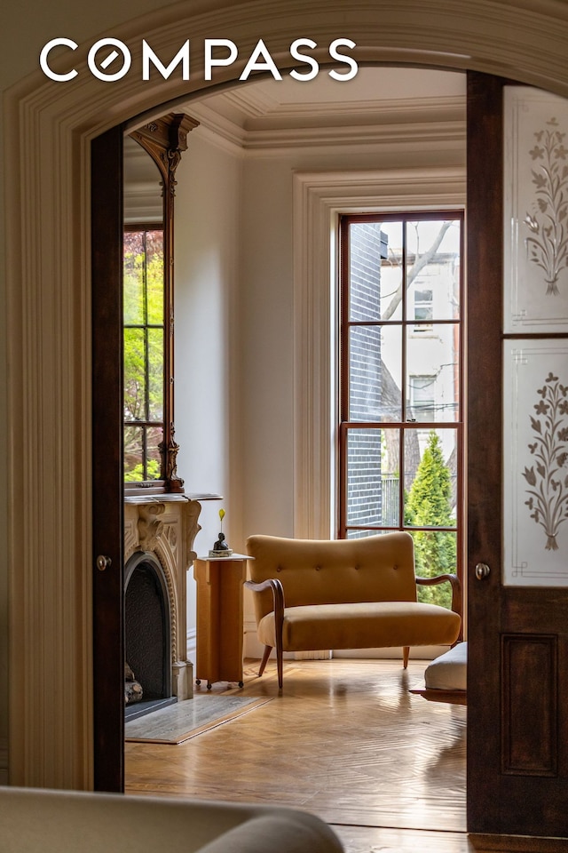 living area featuring wood finished floors, ornamental molding, and arched walkways