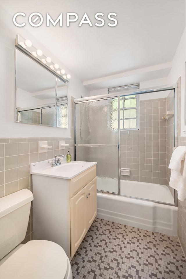 347 E 53rd St Unit 9C, New York City, NY 10022 - full bathroom with toilet, tile walls, vanity, enclosed tub / shower combo, and tile patterned floors