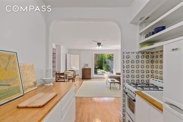 322 W 88th St Unit B, New York City, NY 10024 - kitchen featuring white appliances, arched walkways, white cabinetry, light wood-type flooring, and ceiling fan