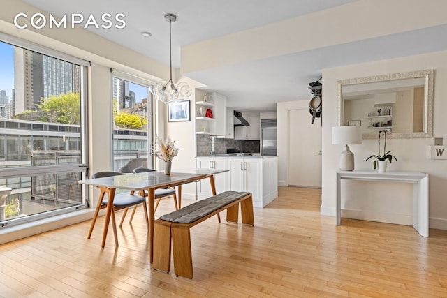 146-148 W 22nd St Ph, Ph, New York City, NY 10011 - dining room featuring light wood-type flooring, a chandelier, a view of city, and baseboards
