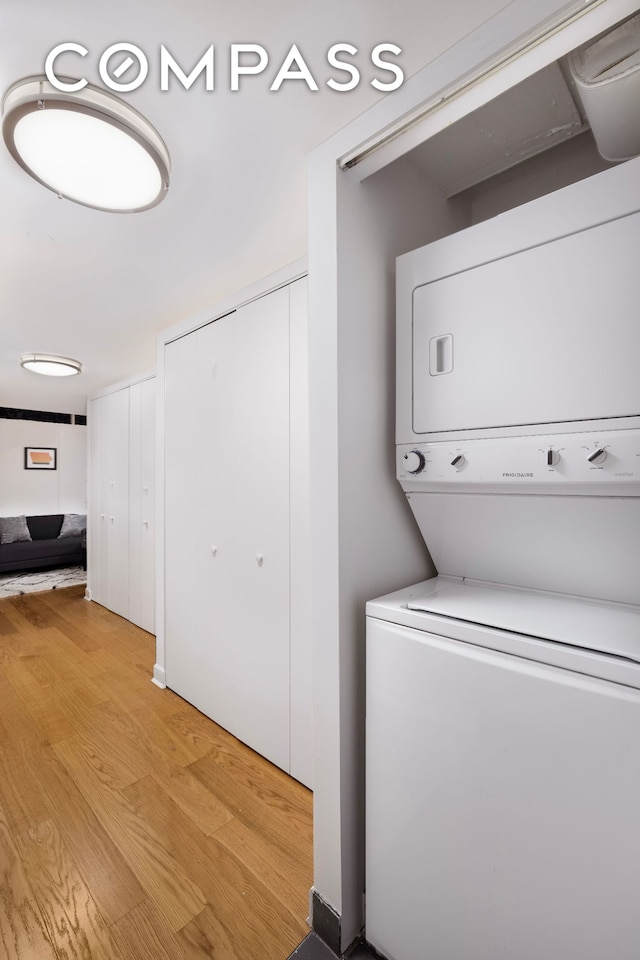 laundry room with stacked washing machine and dryer and light wood finished floors
