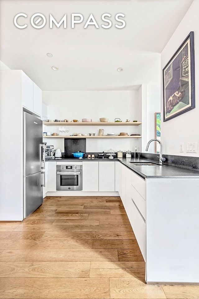 1404 Bushwick Ave Unit 1R, New York City, NY 11207 - kitchen with open shelves, appliances with stainless steel finishes, dark countertops, a sink, and modern cabinets