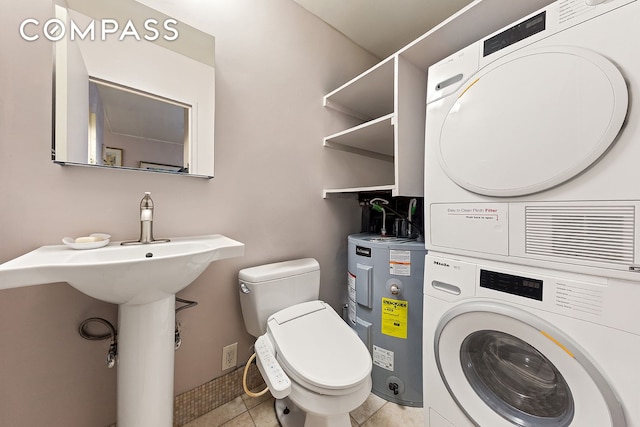 680 Washington St Unit 1B, New York City, NY 10014 - bathroom featuring stacked washing machine and dryer, electric water heater, toilet, and tile patterned flooring