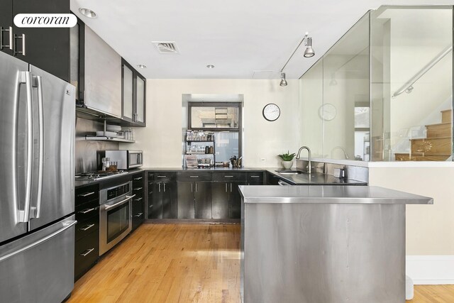 50 Pine St Unit Ph12N, New York City, NY 10005 - kitchen with appliances with stainless steel finishes, stainless steel countertops, light wood-type flooring, a peninsula, and rail lighting