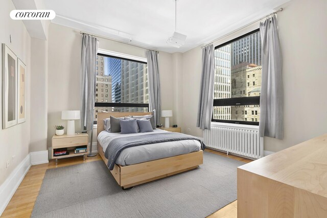 50 Pine St Unit Ph12N, New York City, NY 10005 - bedroom featuring radiator heating unit, wood finished floors, and a view of city