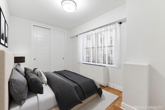 bedroom featuring a closet, baseboards, and parquet floors