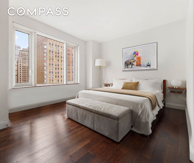 bedroom with baseboards and dark wood-type flooring