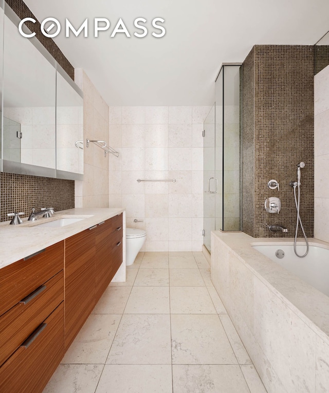 full bathroom with tile walls, a stall shower, toilet, vanity, and tiled tub