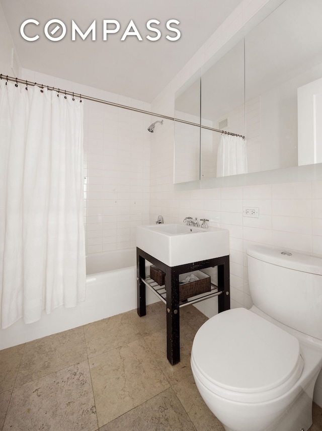 full bathroom with toilet, shower / tub combo with curtain, and tile walls
