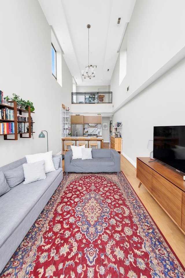 living area featuring wood finished floors, a high ceiling, and a chandelier