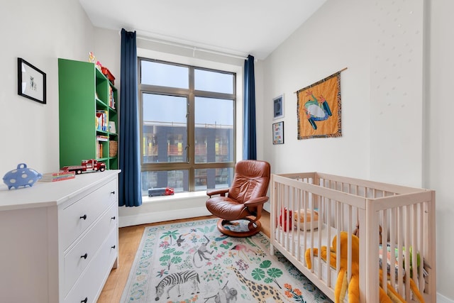 bedroom featuring light wood-type flooring and a crib