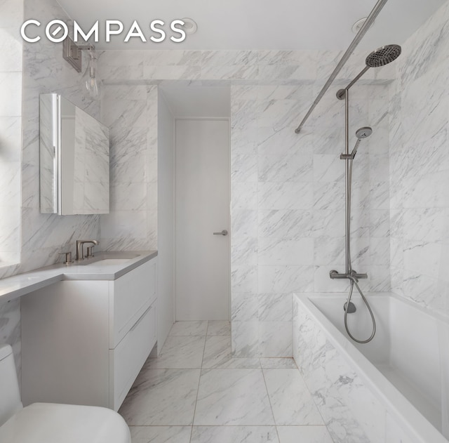 full bathroom with vanity, toilet, marble finish flooring, and tile walls