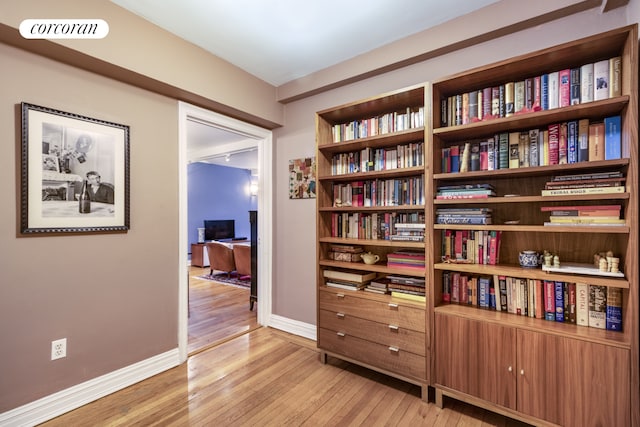 sitting room featuring light wood-style flooring, baseboards, and a desk