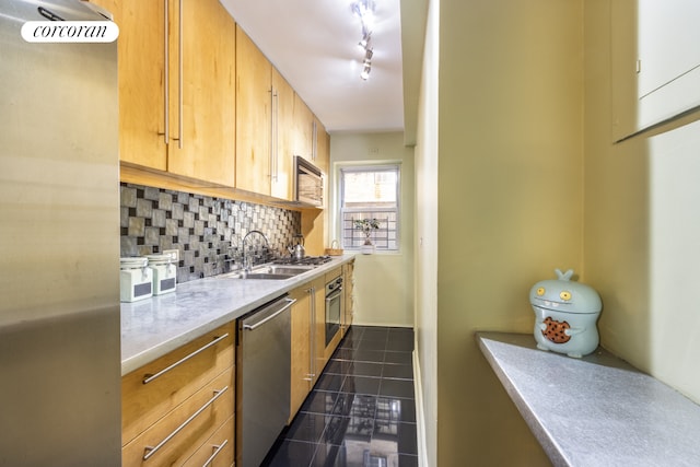 kitchen featuring appliances with stainless steel finishes, a sink, tasteful backsplash, and dark tile patterned flooring
