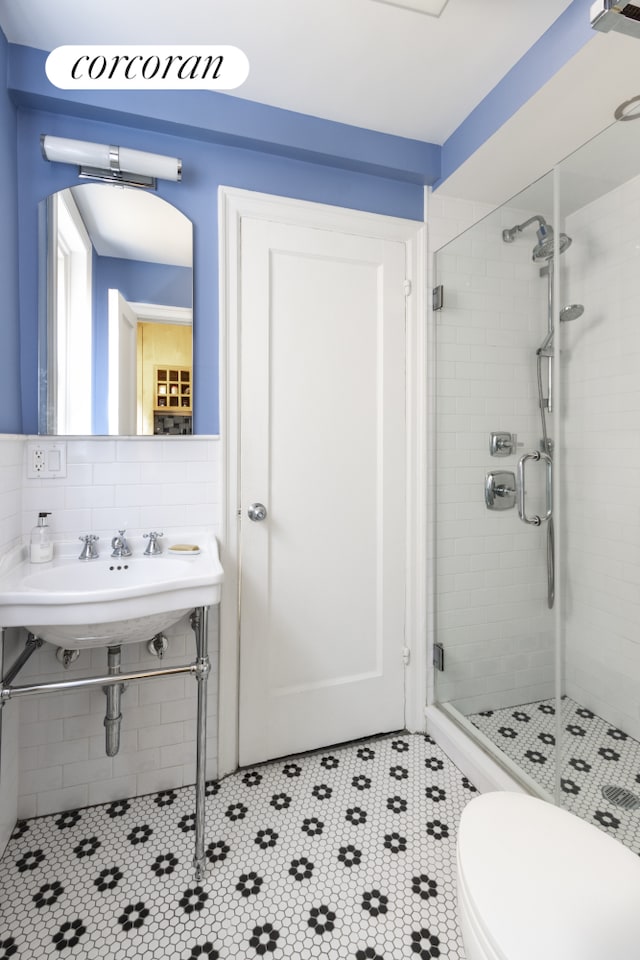 full bath featuring a stall shower, tile patterned flooring, a sink, and toilet