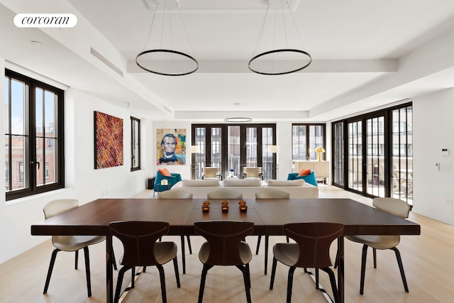 dining area with light wood finished floors and a raised ceiling