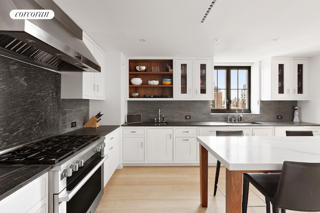 kitchen with range with two ovens, wall chimney range hood, a sink, decorative backsplash, and recessed lighting