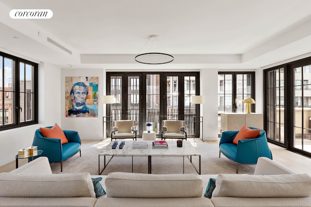 living room featuring carpet, plenty of natural light, and a tray ceiling