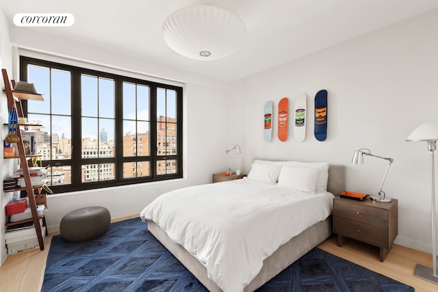 bedroom with wood finished floors, a city view, and baseboards