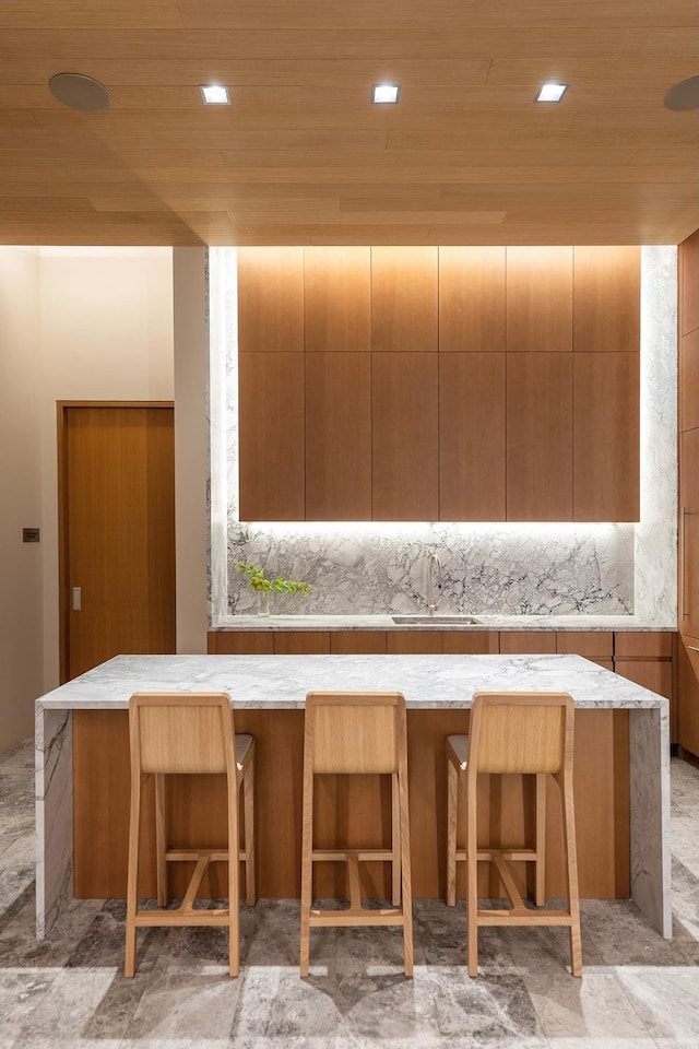 kitchen with a sink, modern cabinets, a breakfast bar, and wood ceiling